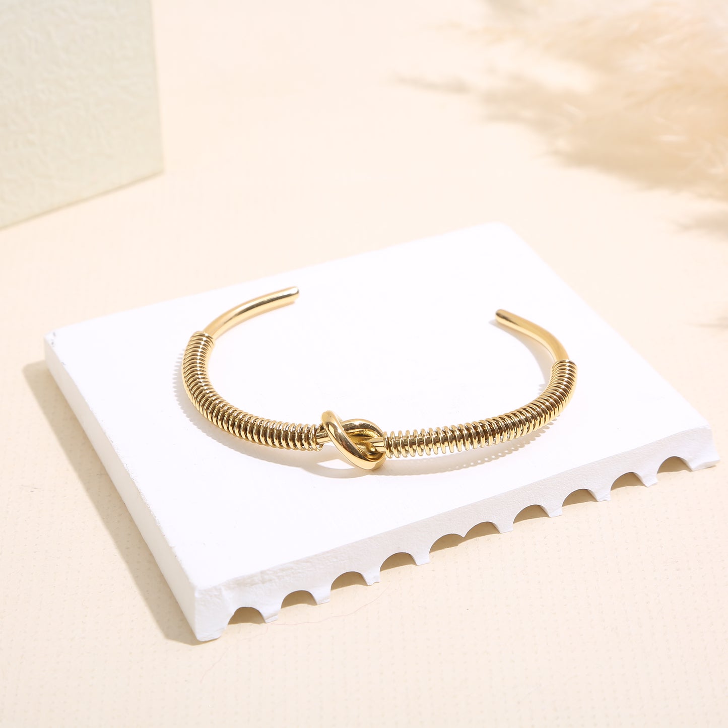 Bracelet jonc doré texturé effet ressort orné d’un nœud central